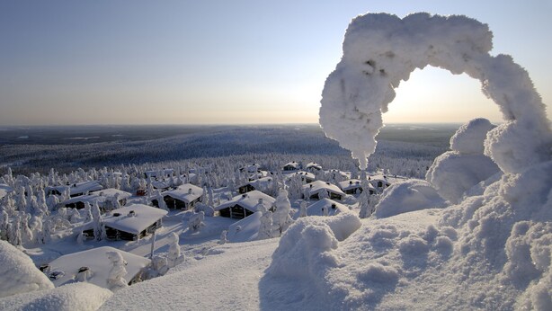 Un village enneigé, avec des maisons et une formation particulière en forme d’arche de neige.