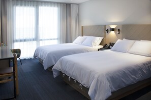 A hotel room with two beds, a desk, and a chair.