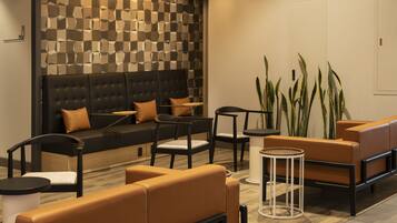Un área de descanso moderna con sofás y sillones de cuero, y una pared con diseño.
