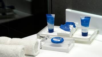 A bathroom with a white sink, two blue toiletry bottles, a blue soap bar, and two white towels on a clear tray.