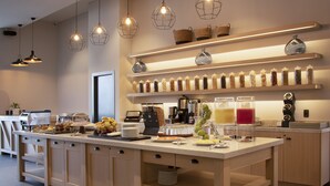 A modern kitchen with a central island, various food items, and a coffee station.