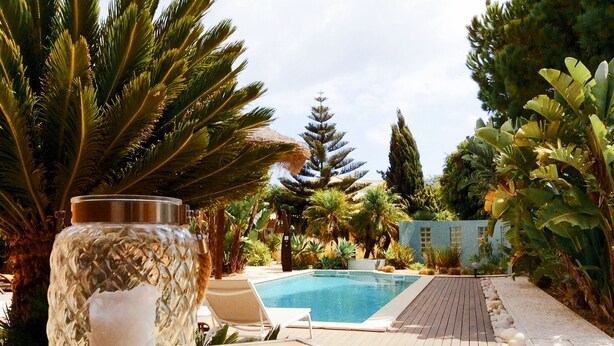 Un espace aménagé au bord de la piscine, avec un bocal en verre, une table en bois et des chaises longues.