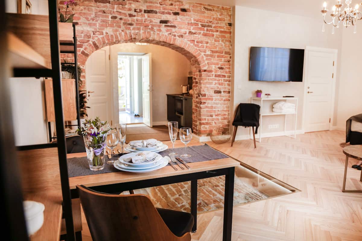 Un comedor con un arco de ladrillo, un televisor montado en la pared y una decoración de estilo moderno.