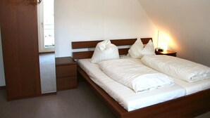 A bedroom with a double bed, a nightstand, and a wooden wardrobe. - Appartementhaus Am Roten Platz (Titisee-Neustadt)