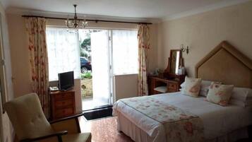 Habitación de hotel con cama, escritorio, silla, televisión y vista al exterior.