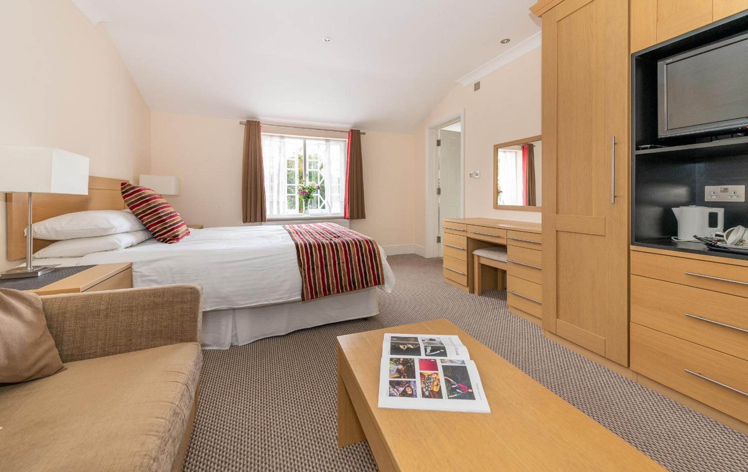 A hotel room with a bed, a desk, a television, and a sofa.