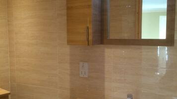 Une salle de bain avec un lavabo blanc, des meubles en bois et un miroir au-dessus du lavabo.