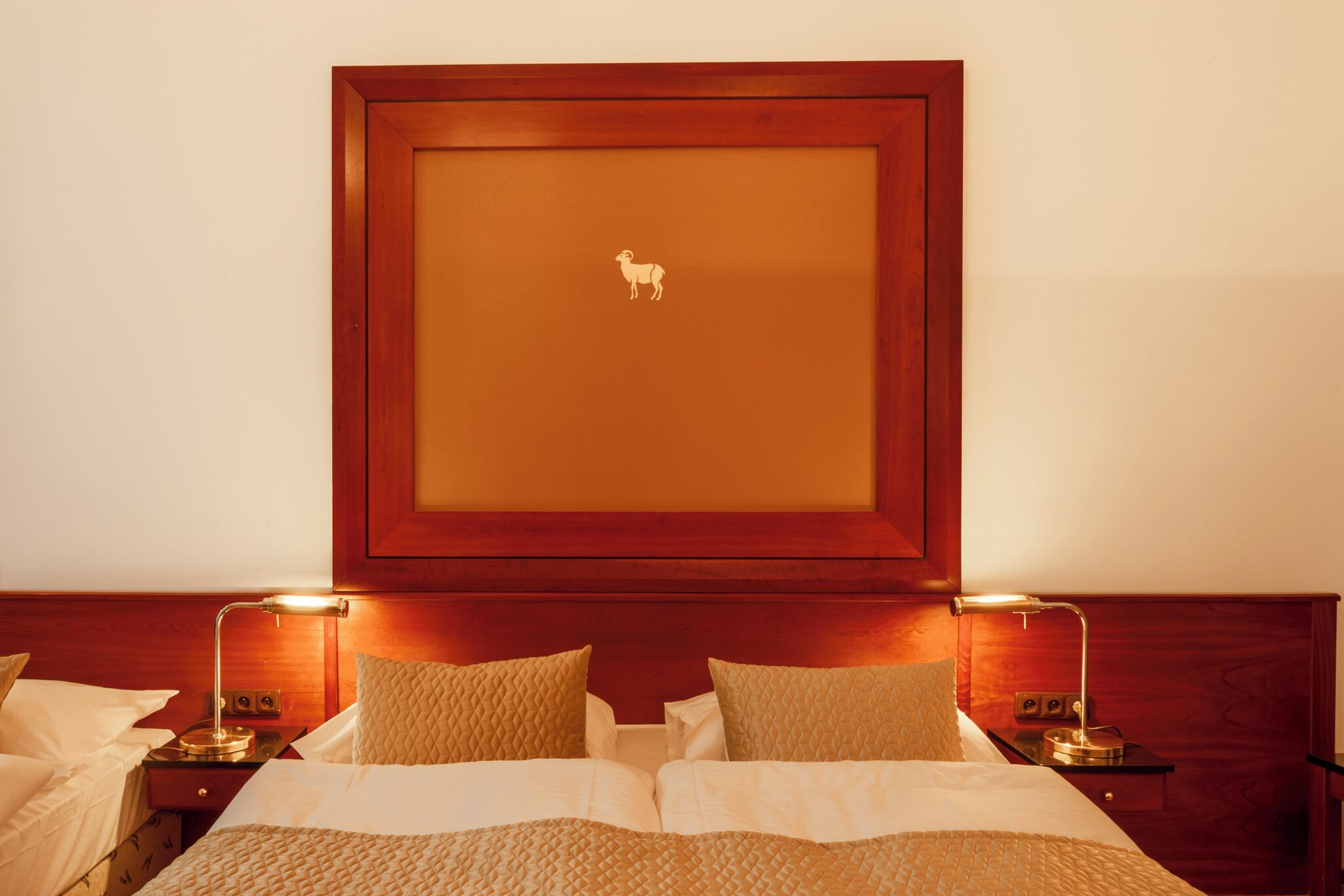 A hotel room with a bed, two bedside tables, and a framed picture on the wall.