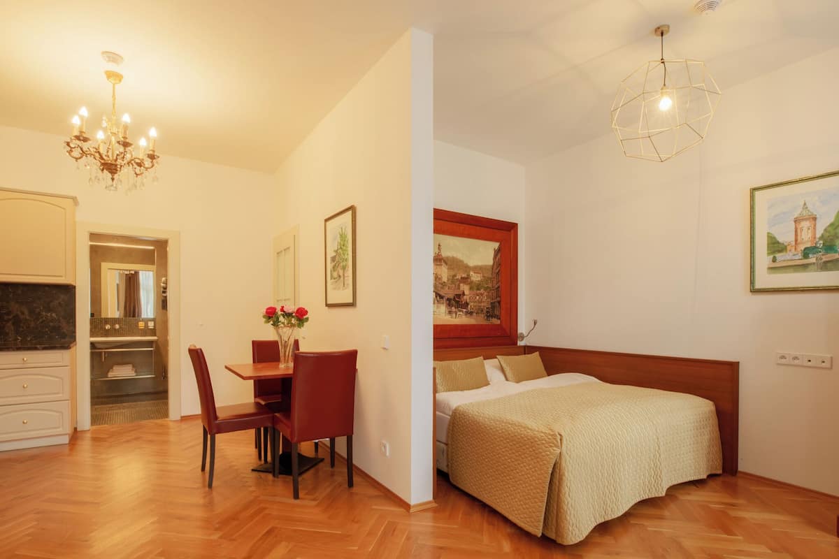 Una habitación de hotel con una cama de madera, un área de comedor con una mesa y sillas, y un candelabro.