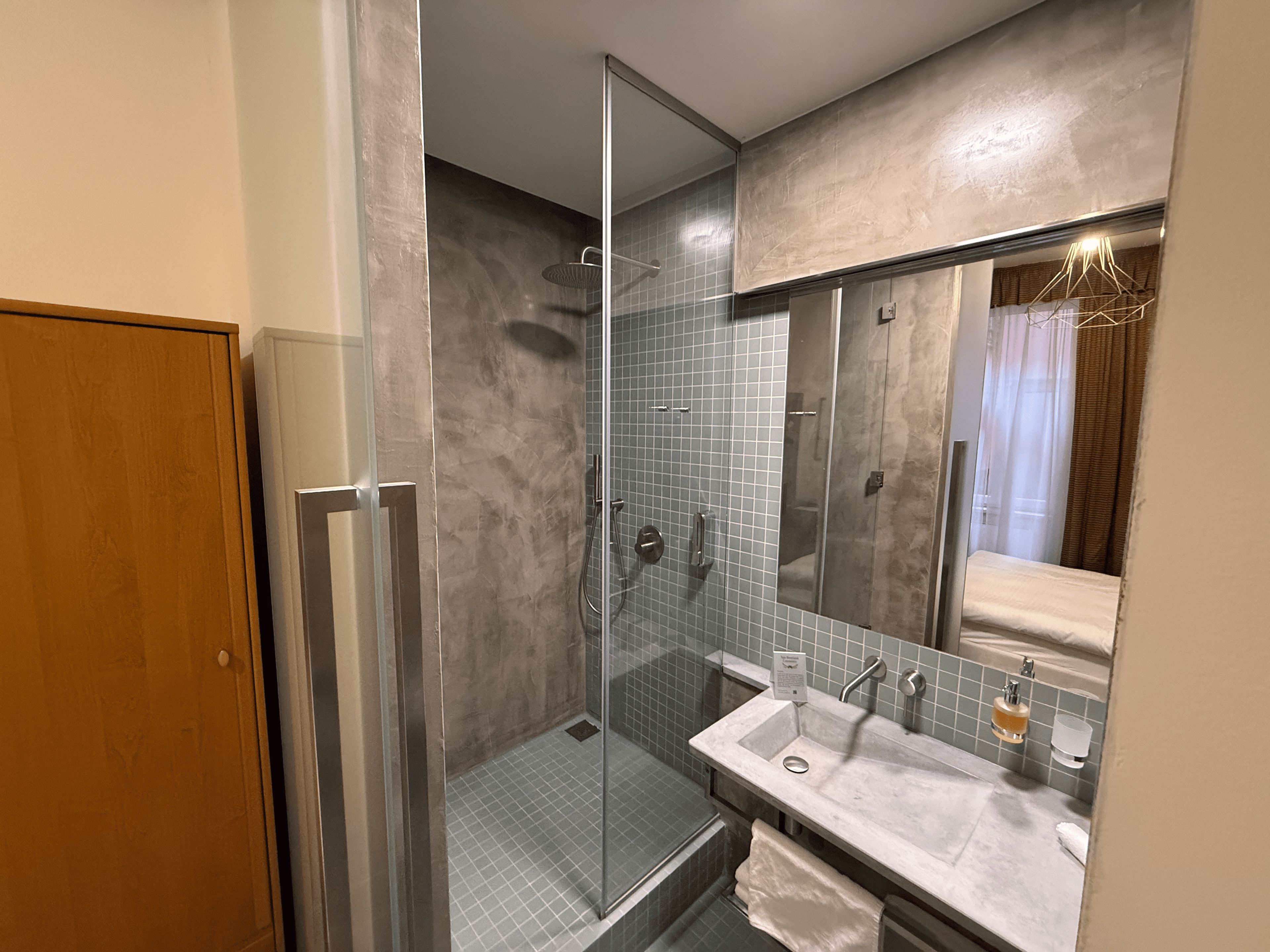 A modern bathroom with a glass-enclosed shower, a sink with a mirror above, and a towel rack.