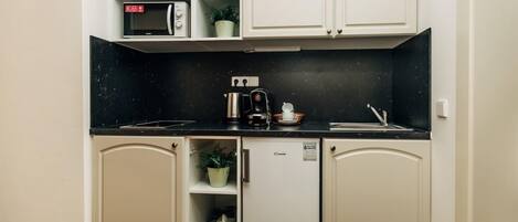 A compact kitchen with a microwave, coffee maker, and refrigerator.