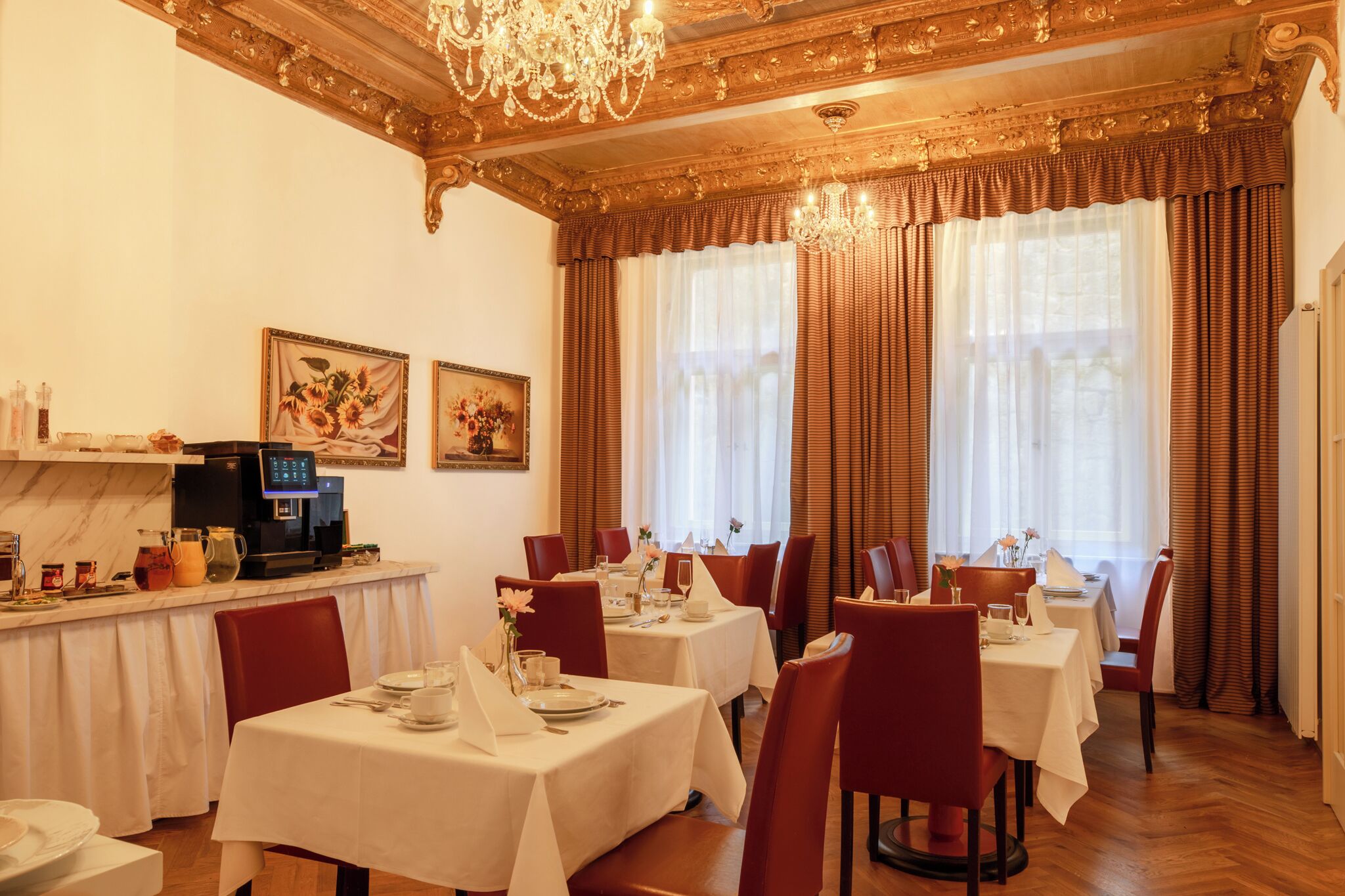 Un espace repas avec des tables dressées, une machine à café et des œuvres d’art accrochées aux murs.