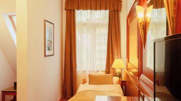 A hotel room with a bed, a bedside table, a lamp, and a television.