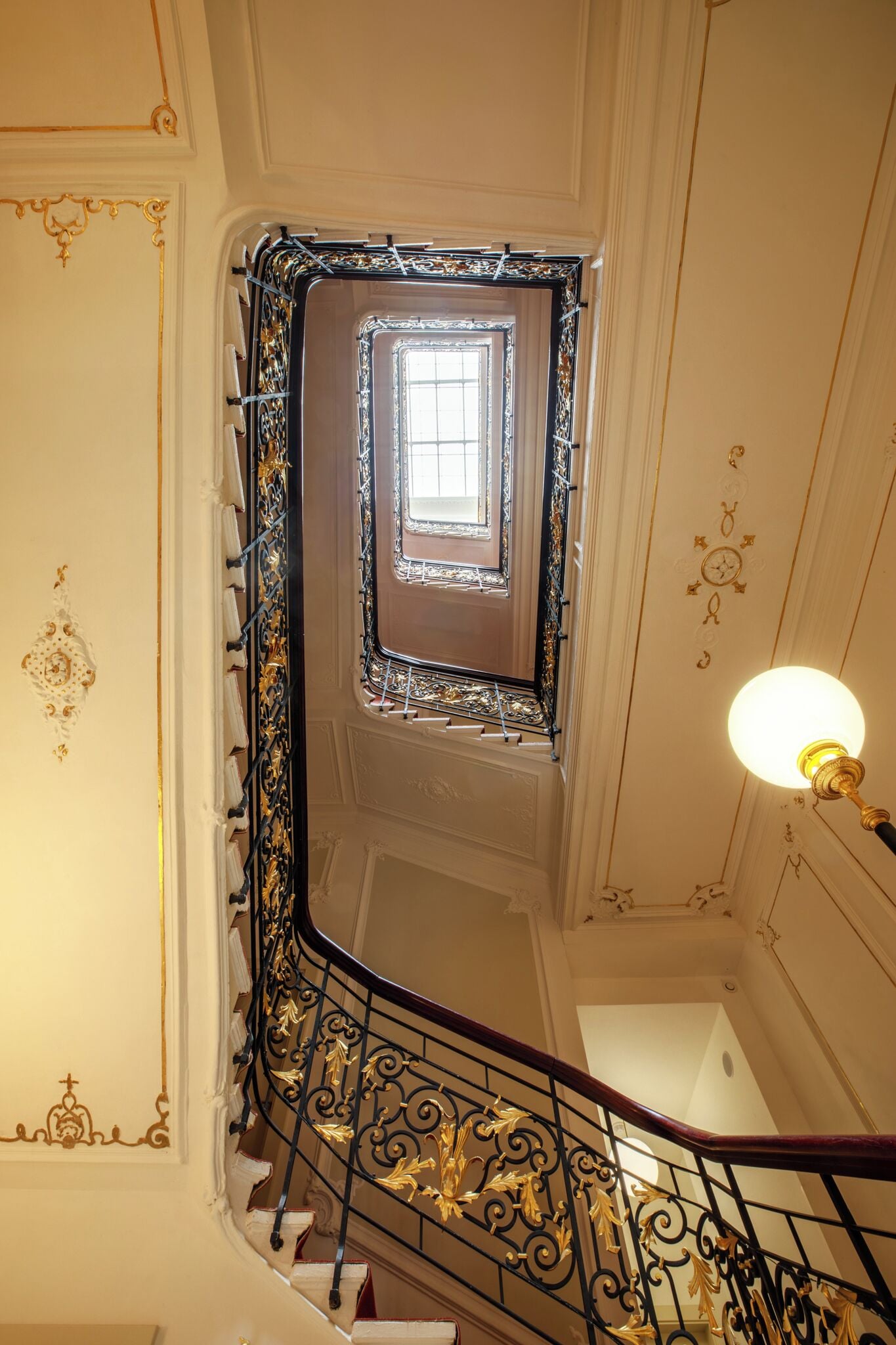 A grand staircase with ornate metal railings and a decorative light fixture.