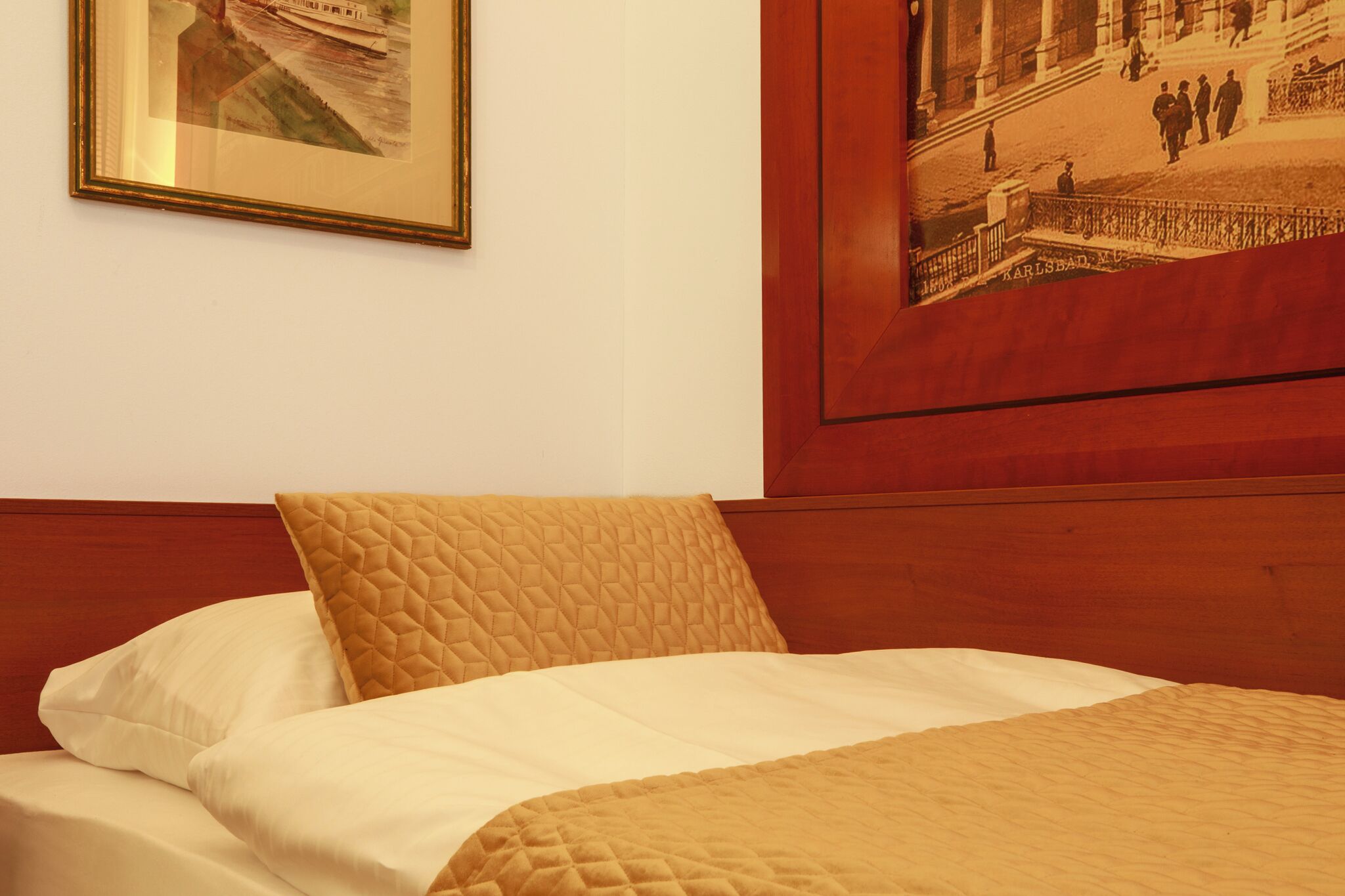 Una habitación de hotel con una cama, un cuadro enmarcado en la pared y un cabecero de madera.