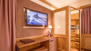 Ein Holzinnenraum mit einem an der Wand befestigten Fernseher, der eine verschneite Berglandschaft zeigt.