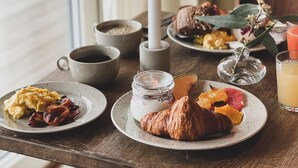A breakfast table with plates of food, a candle, and a glass of orange juice. - Skärgårdshotellet Hönö (Hono)