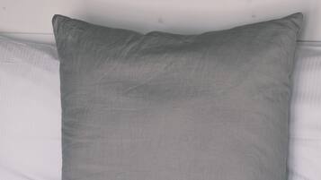 A bed with a gray pillow and a wooden headboard.