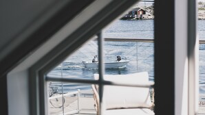 A view from a window overlooking a body of water with a boat and a small building in the distance. - Skärgårdshotellet Hönö (Hono)