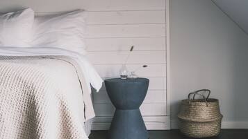 A bedroom with a bed, a bedside table with a vase, and a woven basket.