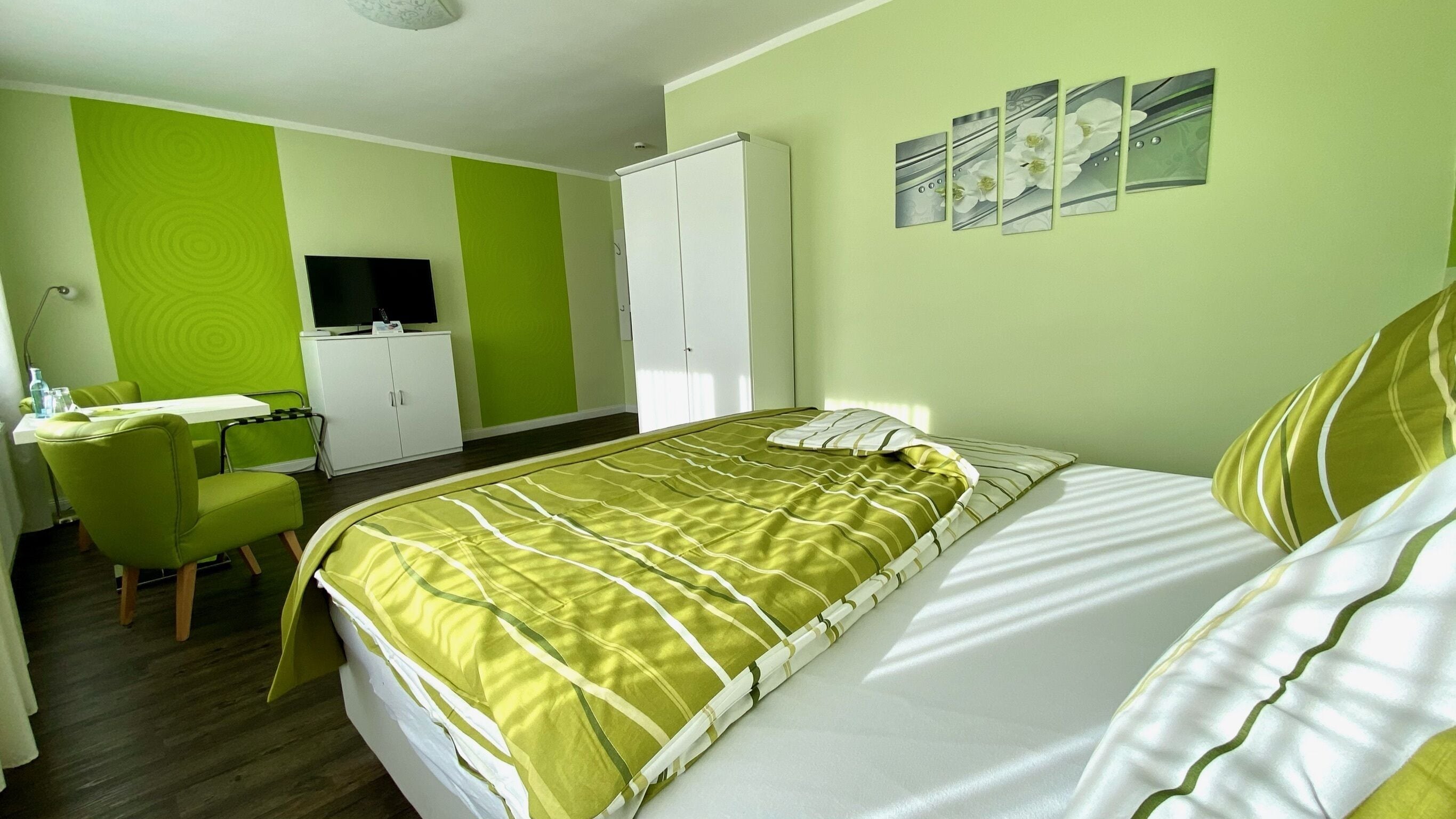 Una habitación de hotel con cama, escritorio, armario y televisión.