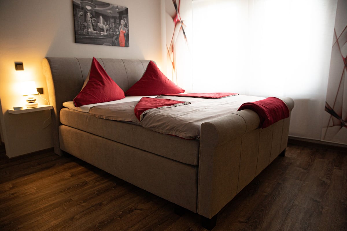 A bedroom with a bed, a nightstand, a lamp, and a painting on the wall.