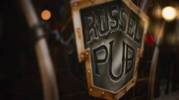 A sign for 'RUSSEL PUB' with a hexagonal shape and riveted edges.