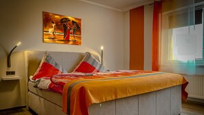 A bedroom with a bed, a painting on the wall, and a window with curtains. - Restaurant & Pension Rüssel - Pub (Sangerhausen)