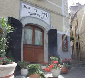 A building with a sign reading "B&B Il Tomolo" and a number "9" above the entrance. There are potted plants in front of the building. - B&B Il Tomolo (Agnone)