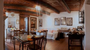 A cozy dining area with wooden furniture, a white sofa, and a kitchen area with a stove and cabinets. - B&B Il Tomolo (Agnone)