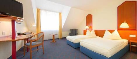 A hotel room with two beds, a desk with a chair, a television, and a window with curtains.