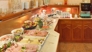 Una mesa de buffet con una variedad de alimentos, como carnes, quesos, frutas y ensaladas.