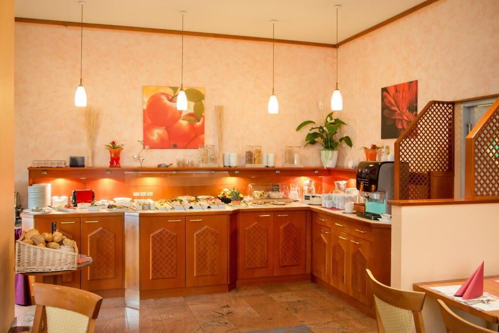 Una cocina con armarios de madera, un mostrador tipo buffet, luces colgantes y una planta en maceta.