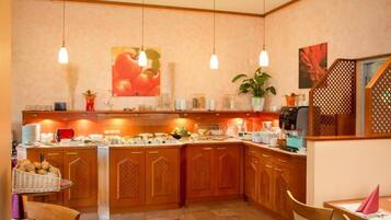 Una cocina con armarios de madera, un mostrador tipo buffet, luces colgantes y una planta en maceta.