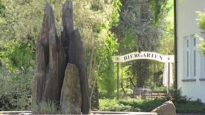 Una escultura de piedra en un área ajardinada con un letrero que dice "Biergarten".
