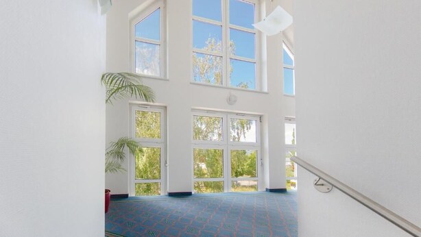 Un interior espacioso con ventanas amplias, piso estampado y una escalera.