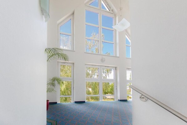 A spacious interior with large windows, a patterned floor, and a staircase. - Montana Hotel Kassel-Süd (Guxhagen)