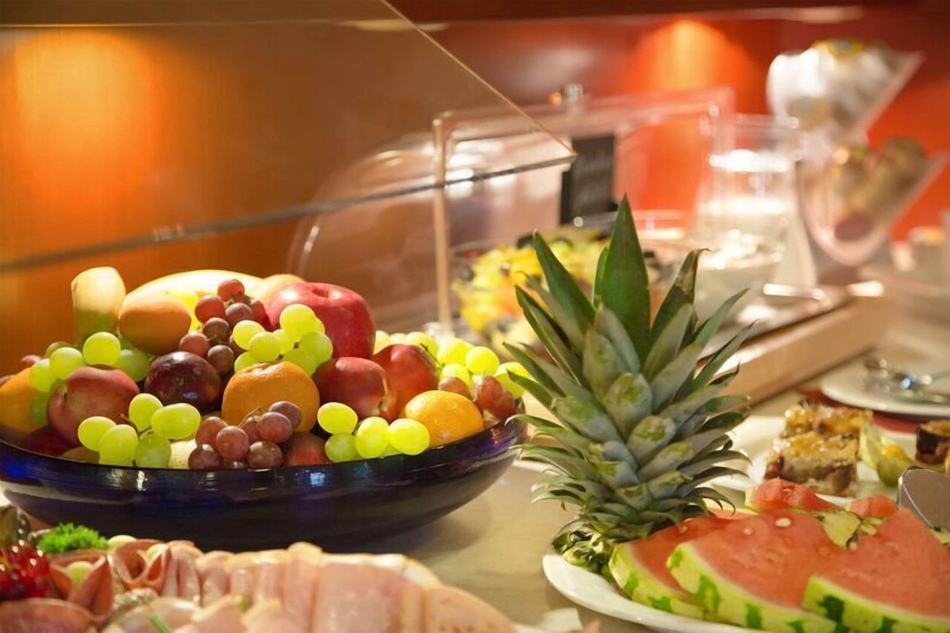 Un buffet con una varietà di frutta e verdura, tra cui uva, mele e anguria.