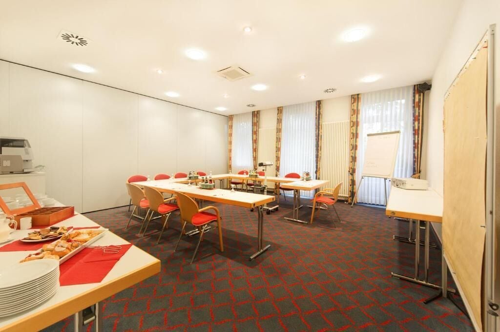 A conference room with tables and chairs, a buffet table with food, and a whiteboard on the wall.