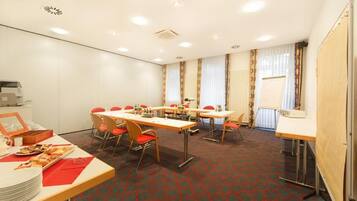 A conference room with tables and chairs, a buffet table with food, and a whiteboard on the wall.