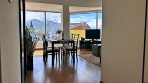 Ein modernes Wohnzimmer mit Essbereich, großen Fenstern und Bergblick.