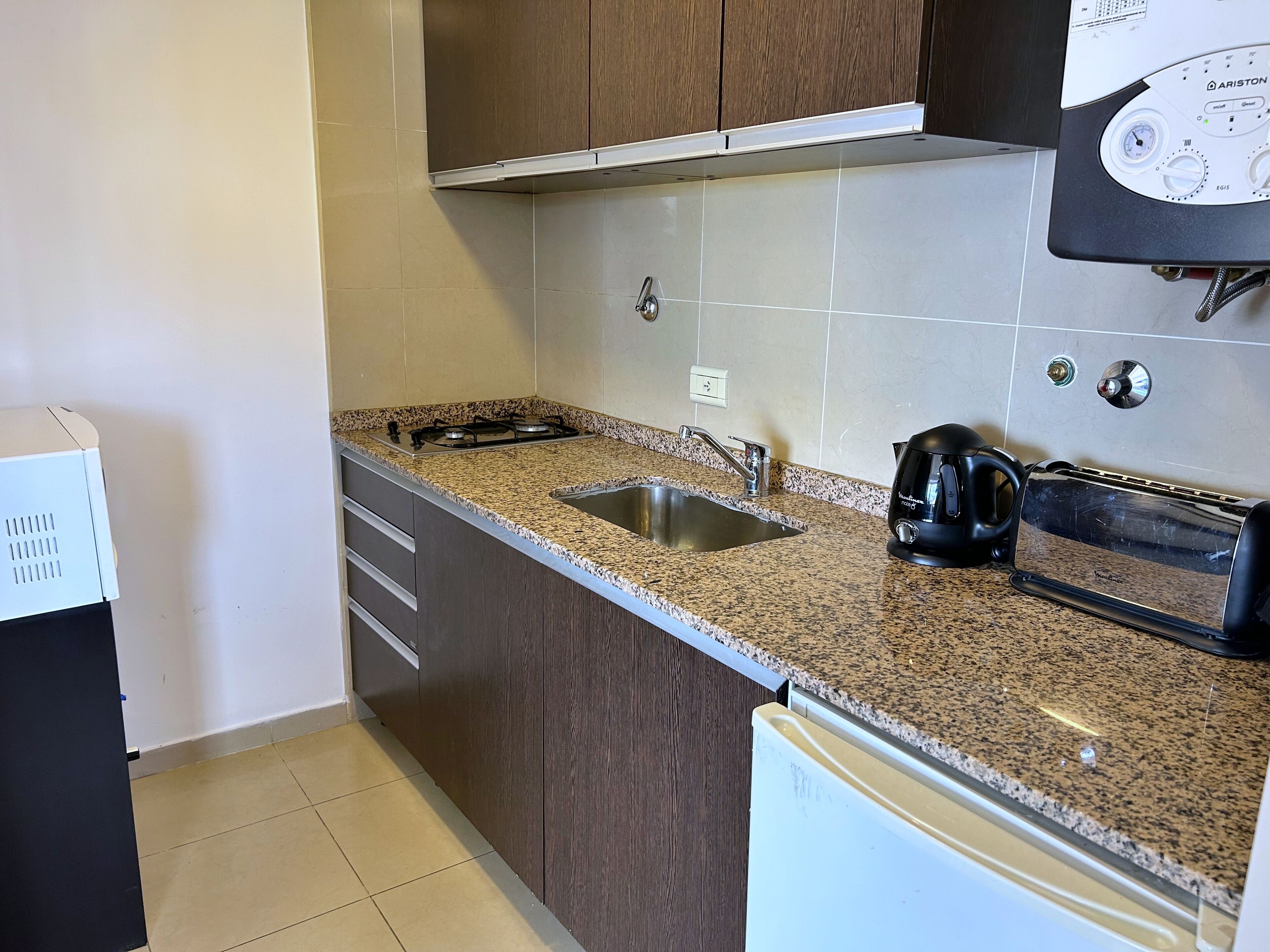 A kitchen with granite countertops, a stainless steel sink, a black coffee maker, and a toaster.