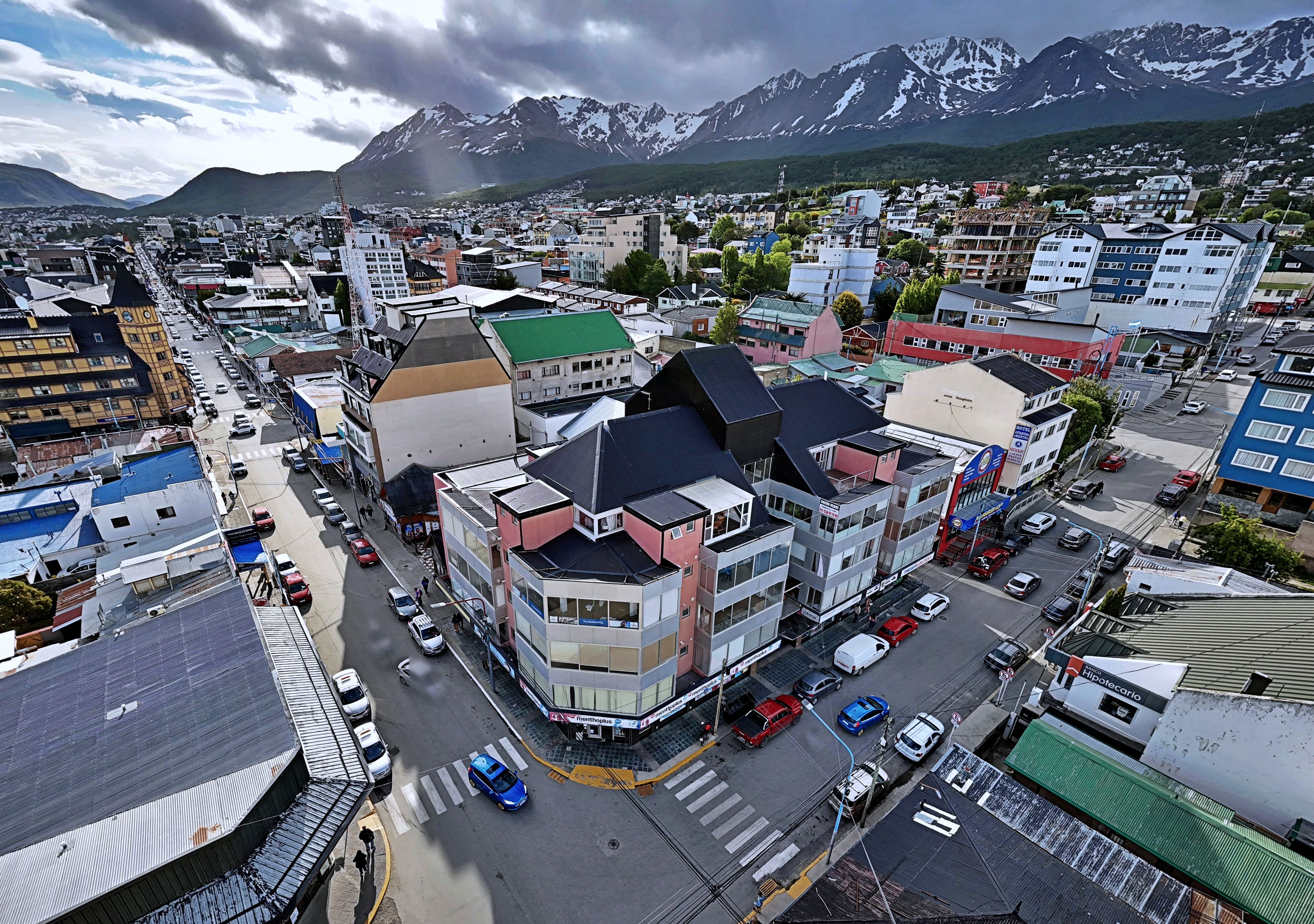 Un immeuble à plusieurs étages doté d’un toit végétalisé, situé dans une ville dont le paysage est dominé par des montagnes.
