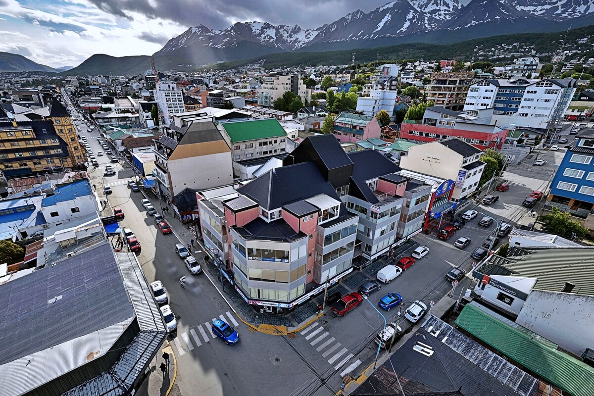 A cityscape with buildings, roads, and mountains in the background.