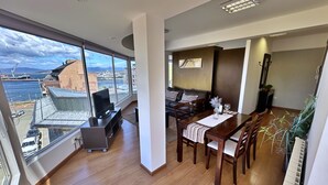 Ein geräumiger Wohnbereich mit großem Fenster und Meer- sowie Stadtblick.