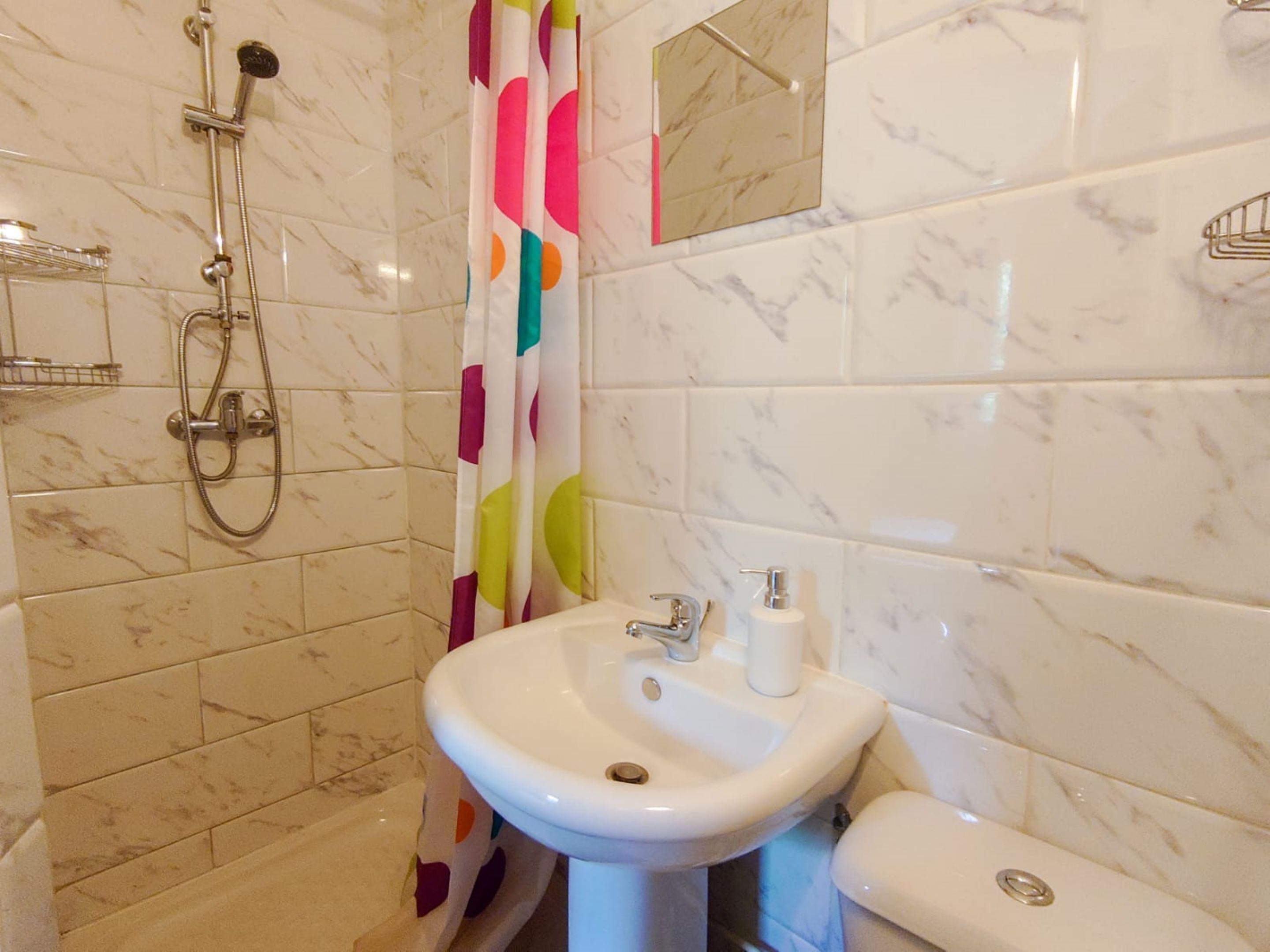 A bathroom with a shower, a sink, and a toilet.