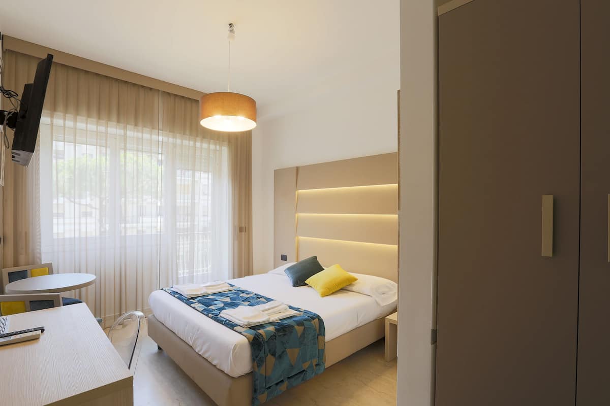 Une chambre d’hôtel moderne équipée d’un lit, d’une table de chevet et d’un bureau avec une chaise.