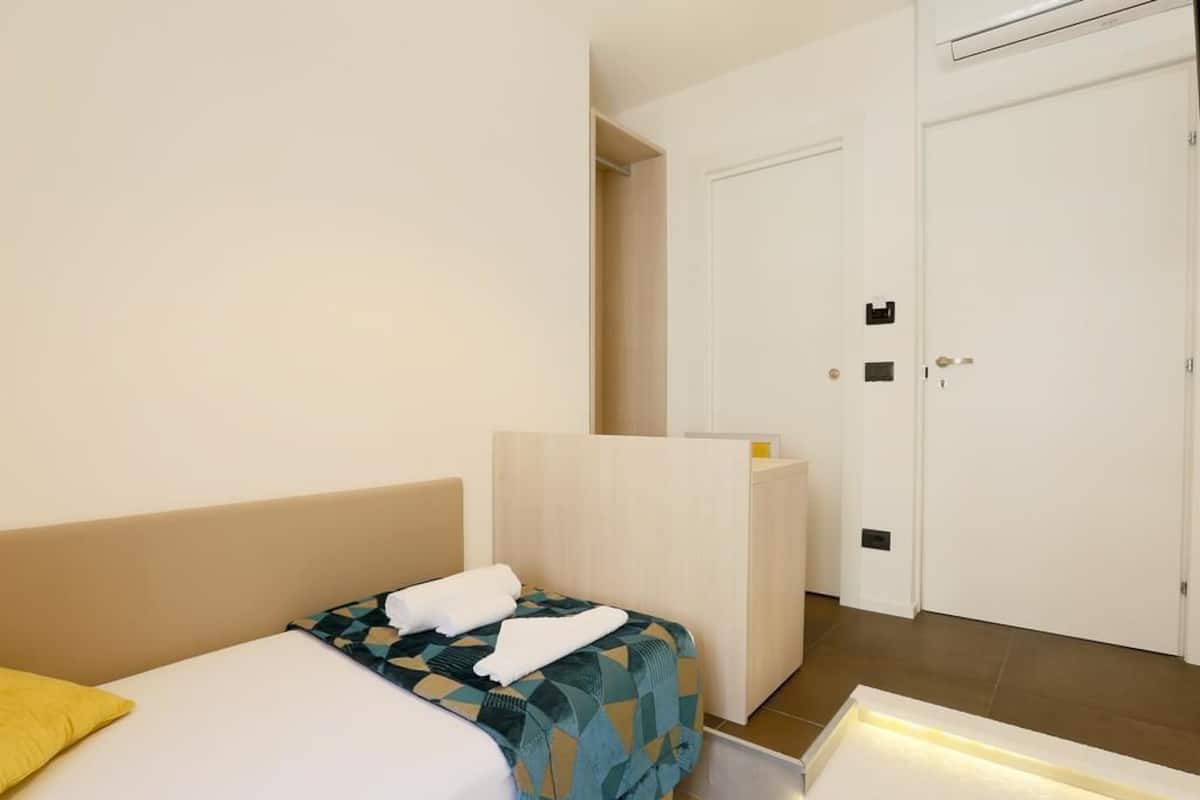 Une chambre d’hôtel avec un lit, un bureau et une armoire.