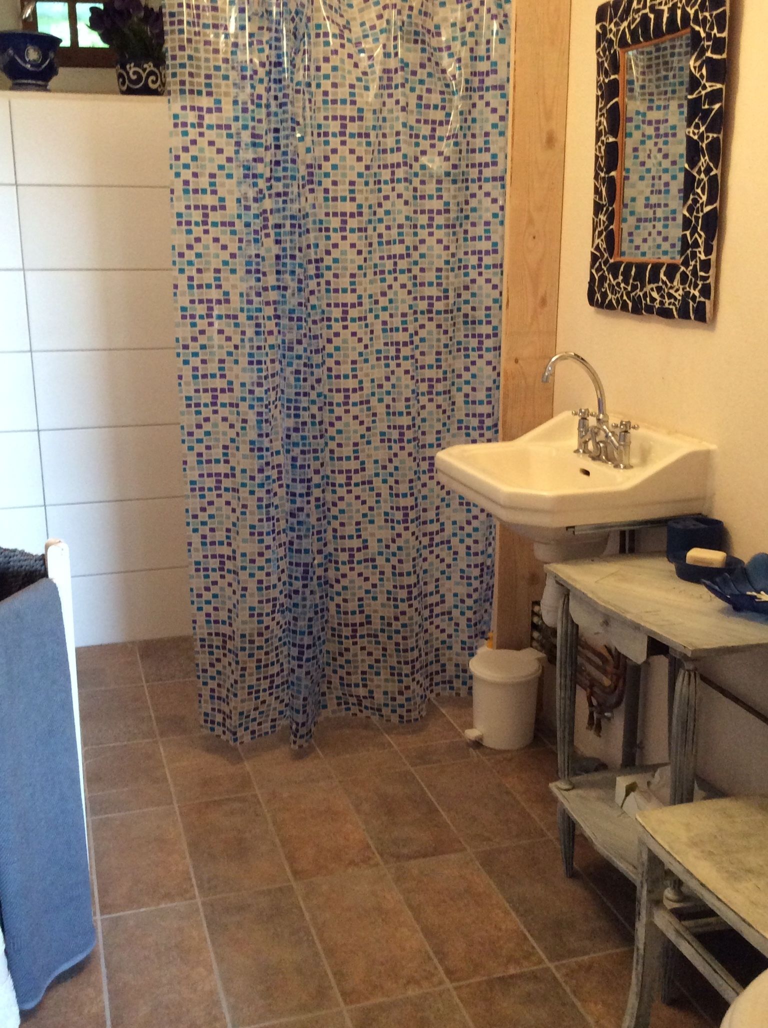 A bathroom with a mosaic shower curtain, a sink, and a mirror.