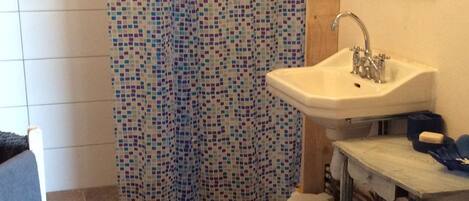 A bathroom with a mosaic shower curtain, a sink, and a mirror.